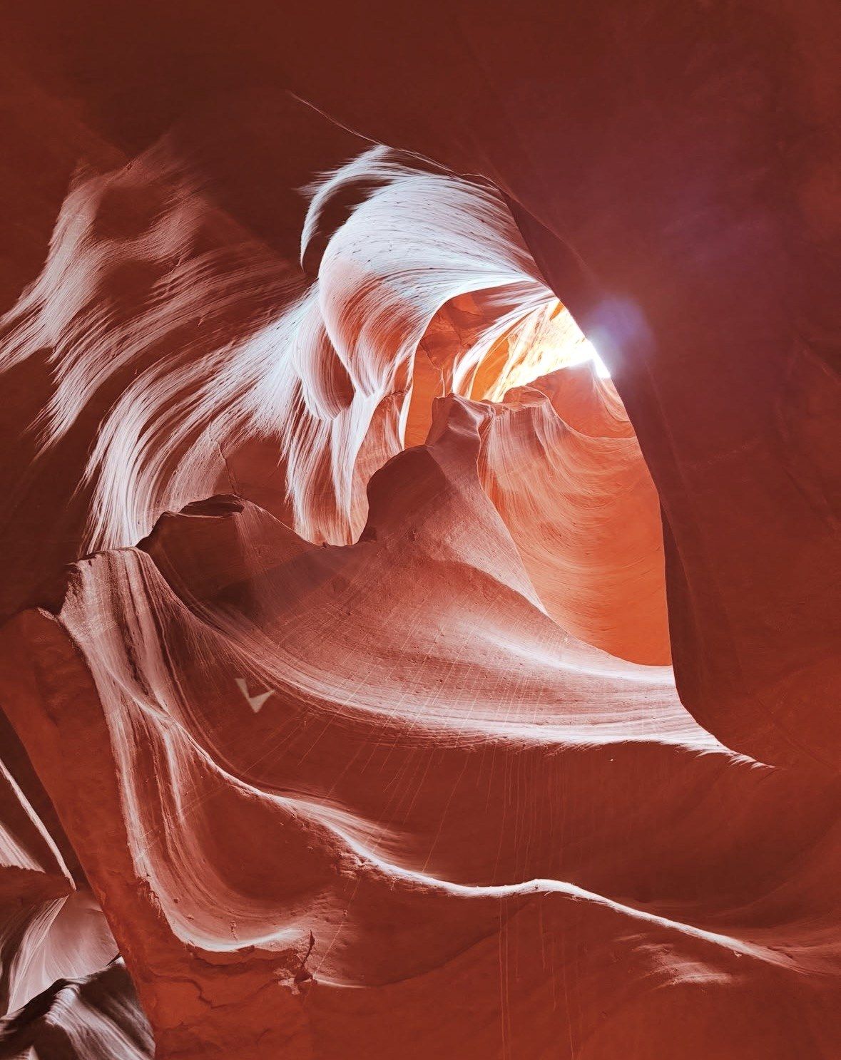 Sunlight breaking through a carved sandstone arch deep in Antelope Canyon
