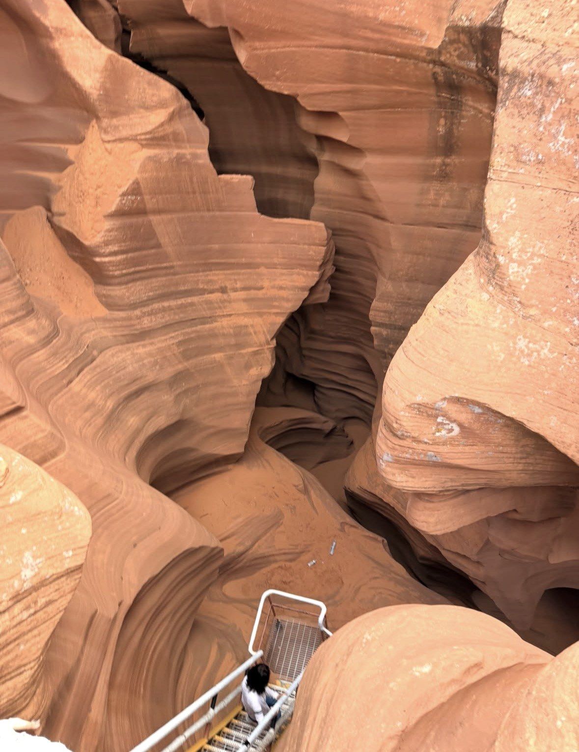 Visitor descending a metal stairway into Lower Antelope Canyon