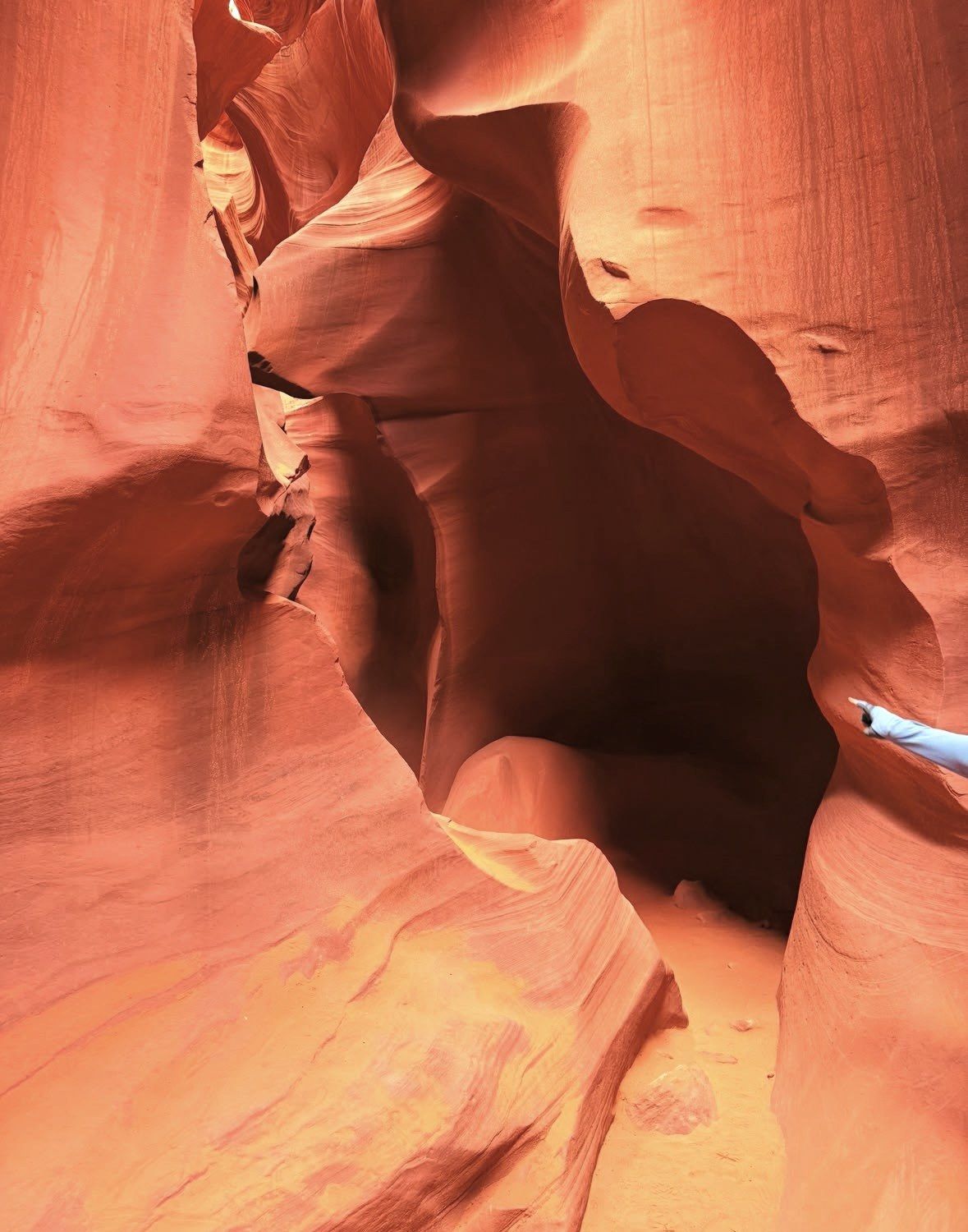 Narrow shaded sandstone passage with sandy floor inside Antelope Canyon
