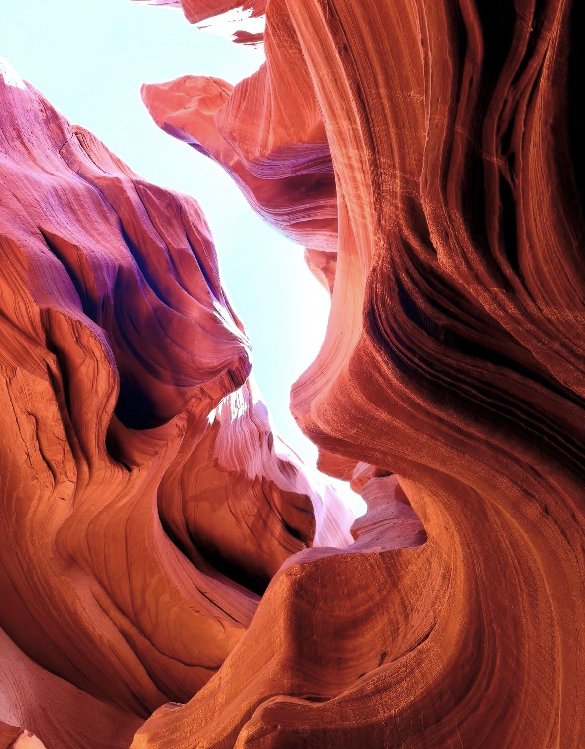 Purple and orange canyon walls meeting under pale daylight sky
