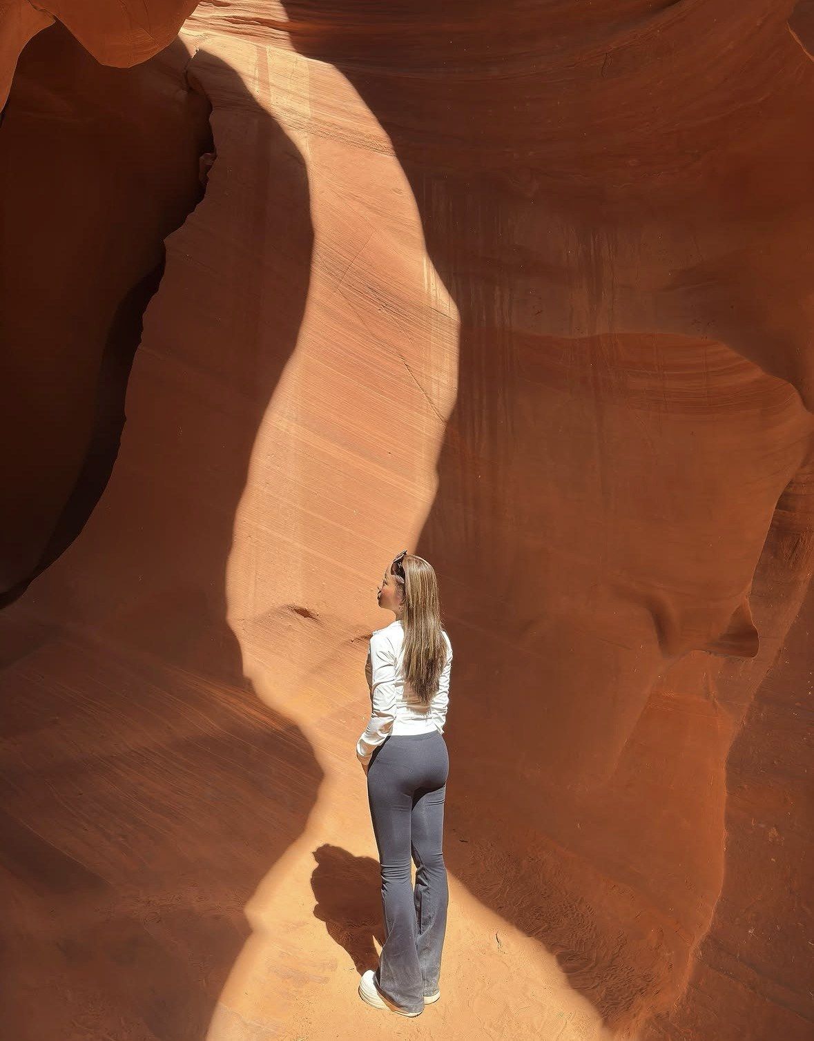 Woman standing in a bright sunlit stripe on the canyon wall