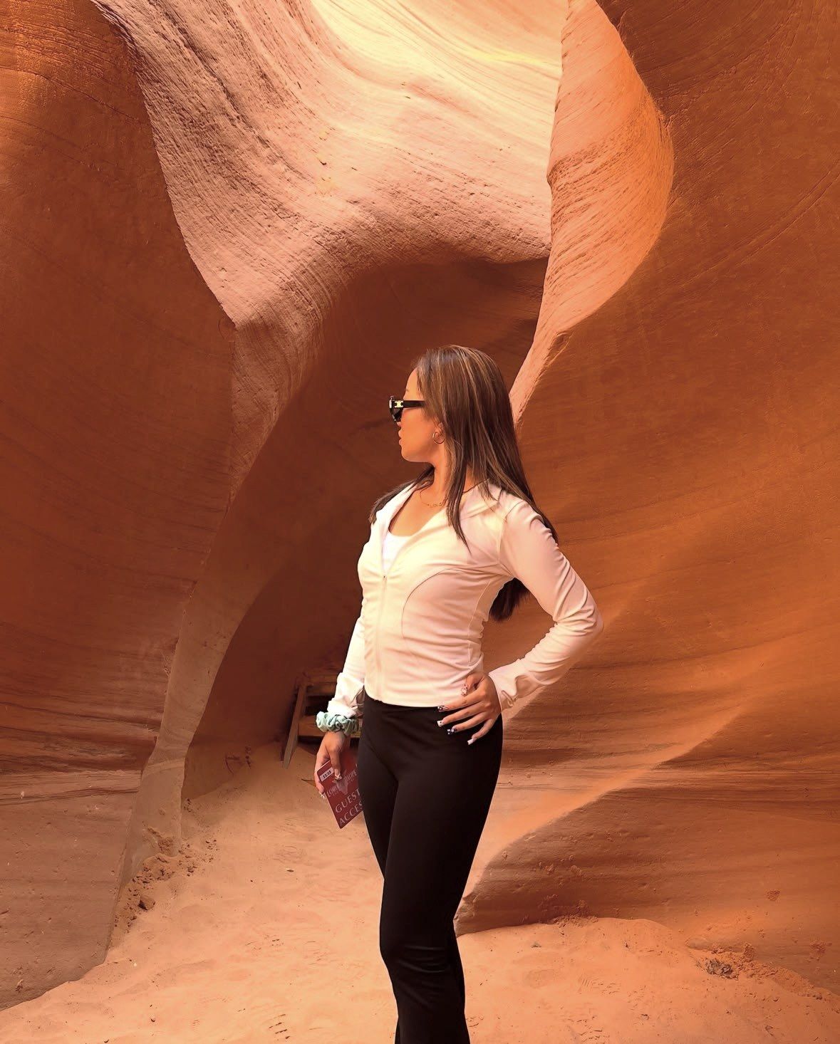 Woman in white shirt and sunglasses standing between curved canyon walls